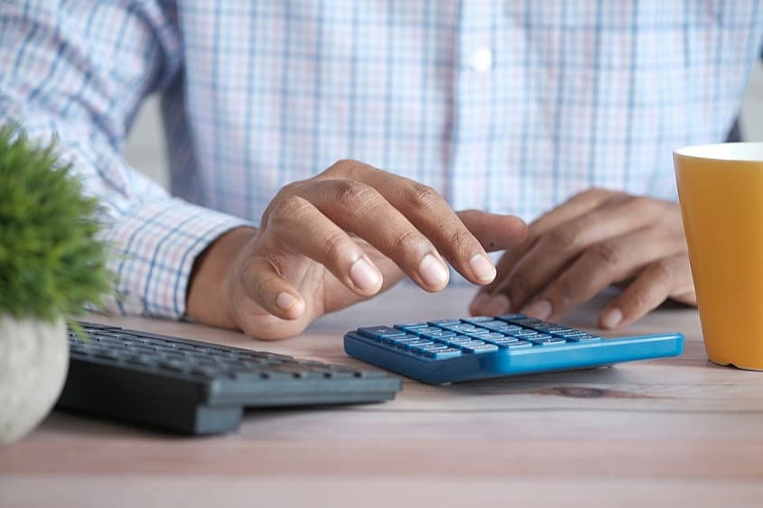 Man using a calculator to reconcile travel expenses
