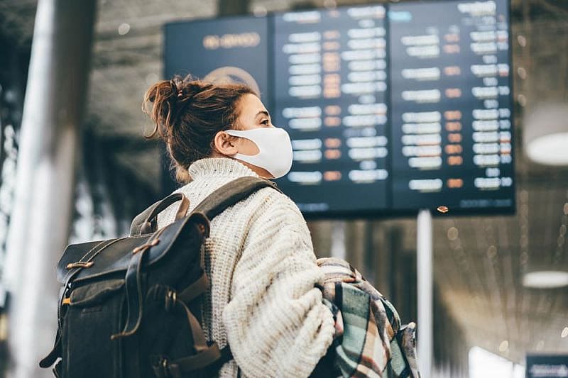 Mujer ante el panel de información del aeropuerto viendo la cancelación de su vuelo por huelga