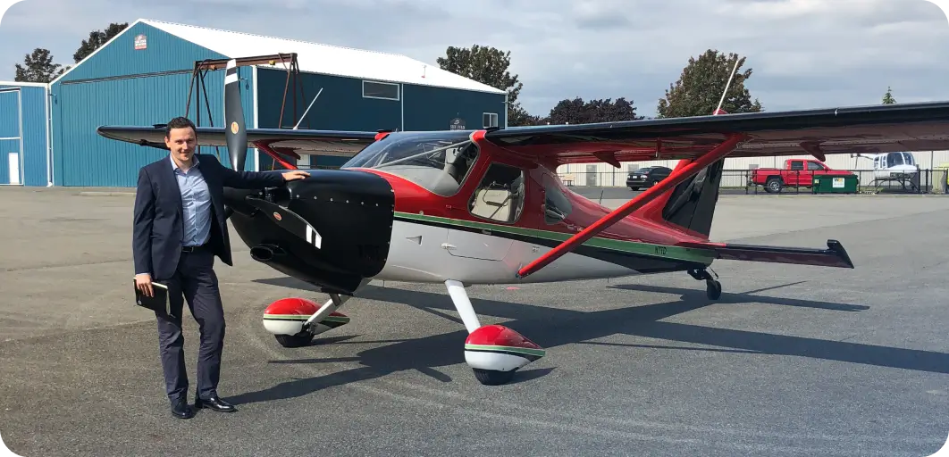 Anton Radchenko ao lado de um pequeno avi&atilde;o a h&eacute;lice num aer&oacute;dromo