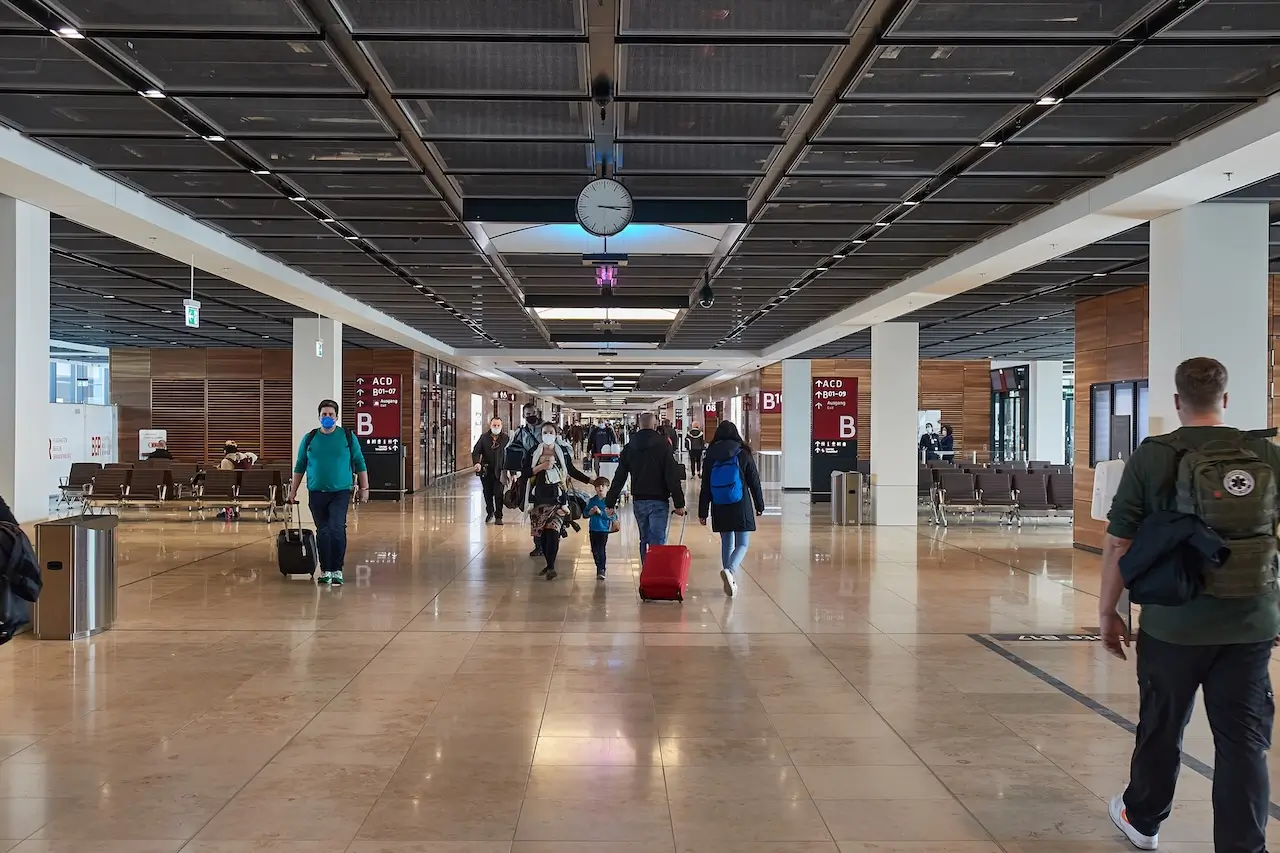 Reisende gehen durch die Abflughalle des Flughafens Berlin-Brandenburg nach einer Flugversp&auml;tung