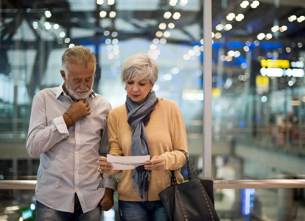 Ouder stel op de luchthaven dat een document bekijkt na melding van een vluchtwijziging