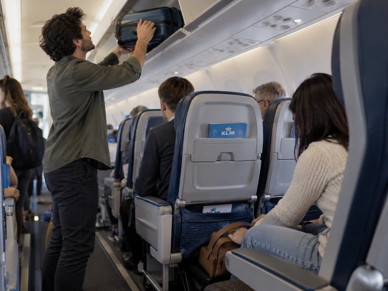 Un pasajero guardando su maleta de mano en el portaequipajes superior de un avi&oacute;n de KLM.