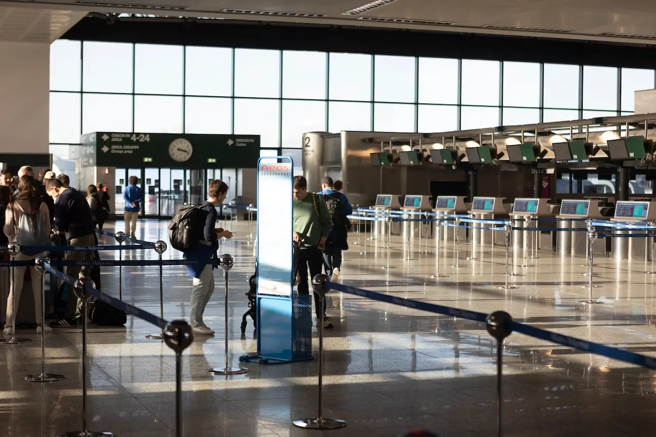 Zona check-in aeroporto Malpensa con persone in coda