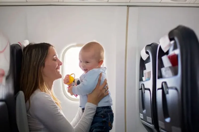 Genrebild över en kvinna som håller sin bebis på flygplanet