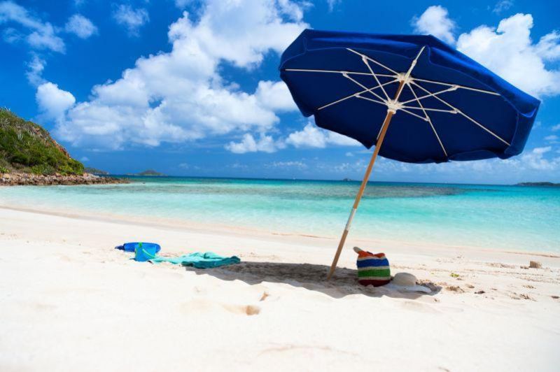 Genrebild över en parasoll på en strand med turkosvatten