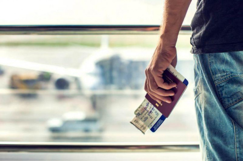 Genrebild över en resenär som håller sitt pass och boardingkort i handen