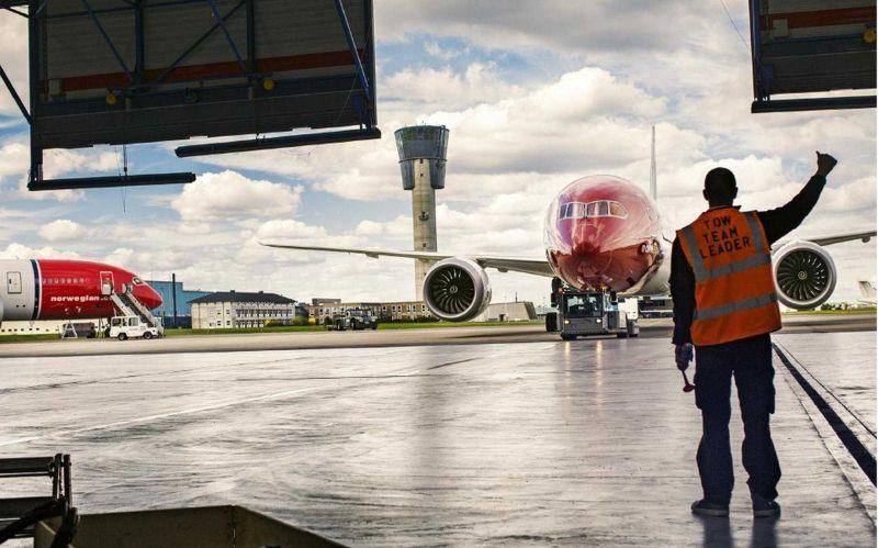 Genrebild på flygplatspersonal som dirigerar ett Norwegian flygplan på marken
