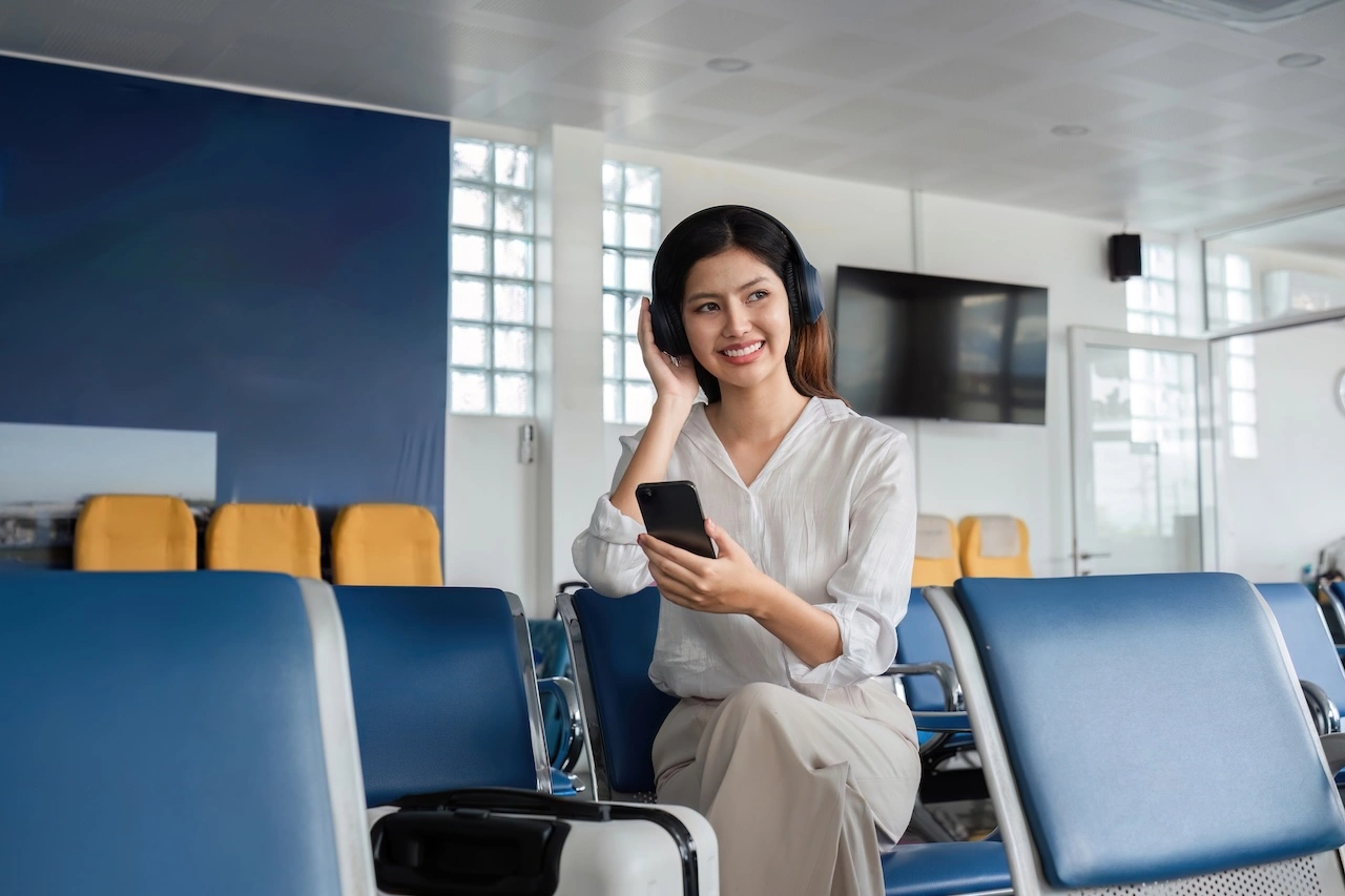 Ragazza seduta in aeroporto che ascolta musica con cuffie