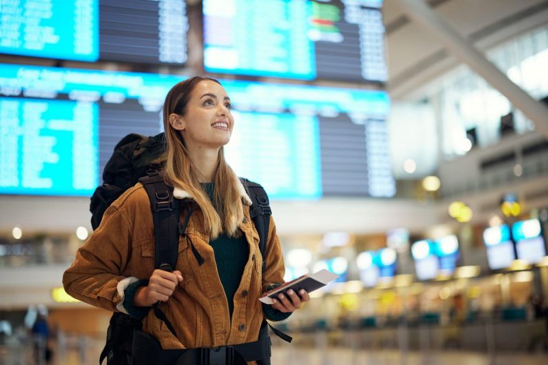 a woman in airport with flight ticket in hand