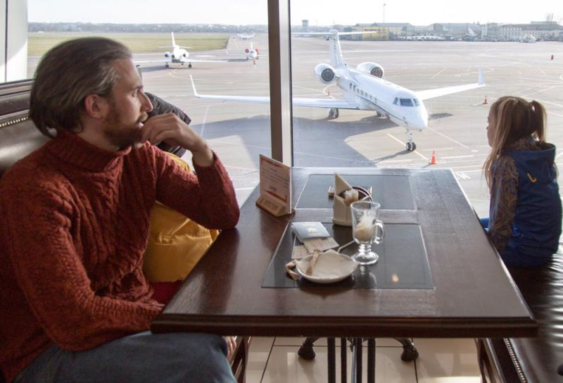 Padre e figlia seduti a un tavolo con vetrata vista aerei