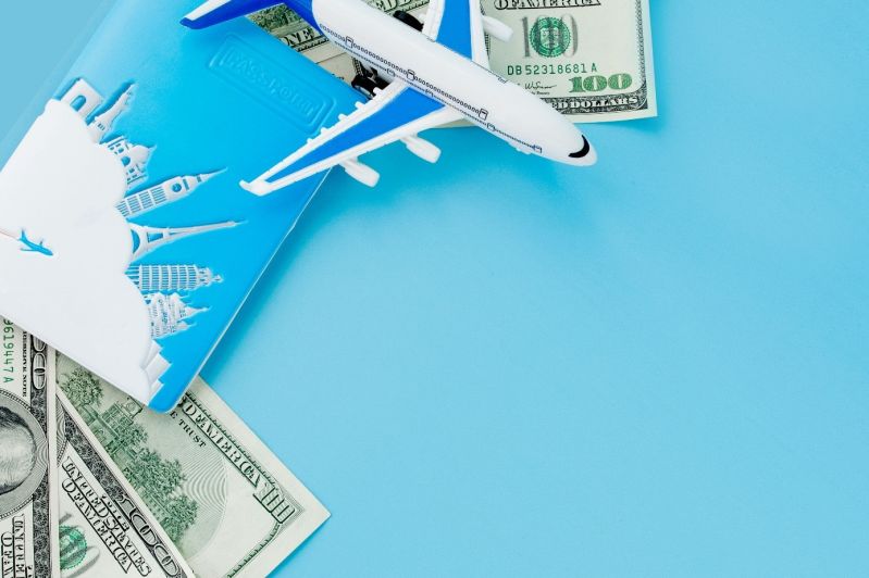 Reisepass mit Modell eines Passagierflugzeugs und Dollars auf blauer Fläche
