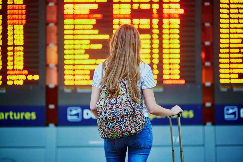 a woman standing in the airport looking at information board