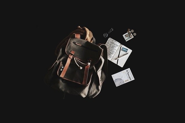 Un sac à dos, à côté de livres, d’un stylo et de pièces