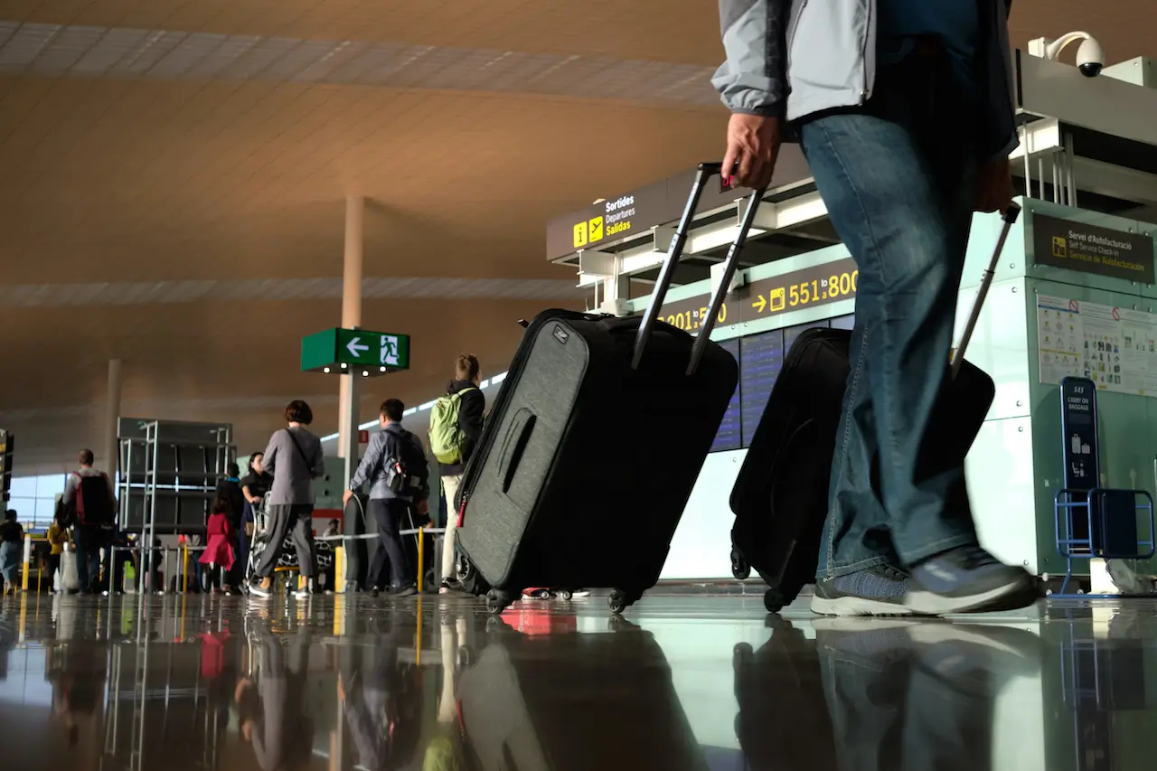 Imagen de viajeros caminando por una terminal de aeropuerto amplia y moderna.