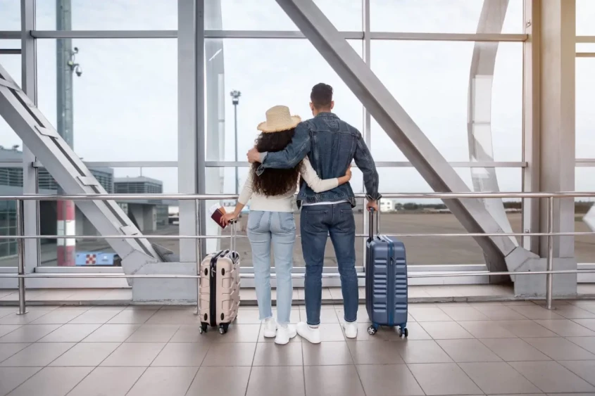 un couple regardant par la fen&ecirc;tre dans le terminal de l'a&eacute;roport