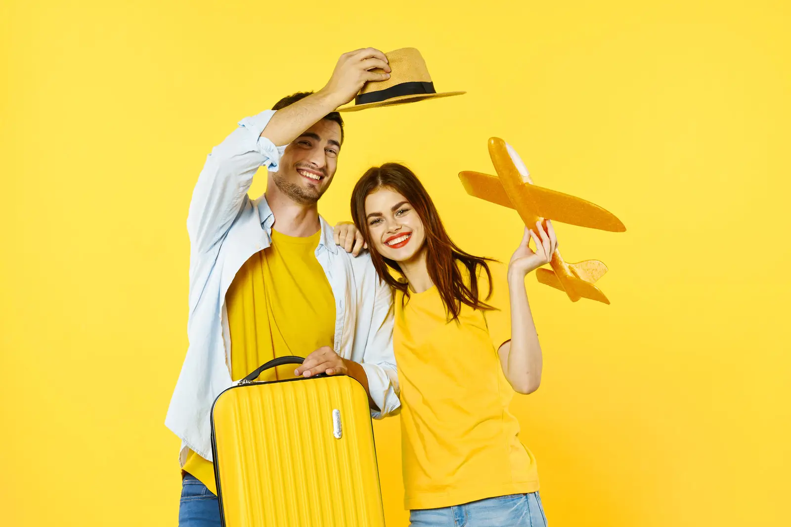 um casal com uma mala amarela e um avião de brincar