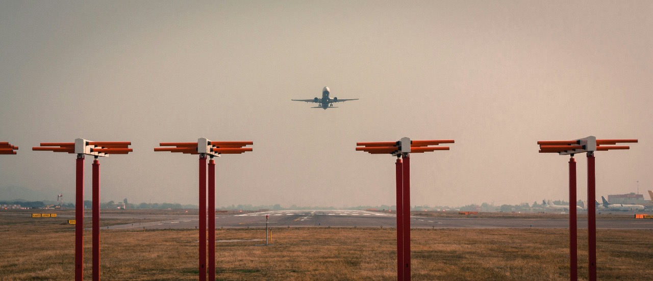 A plane taking off from Milan-Bergamo Airport on a hazy day with red towers in the foreground