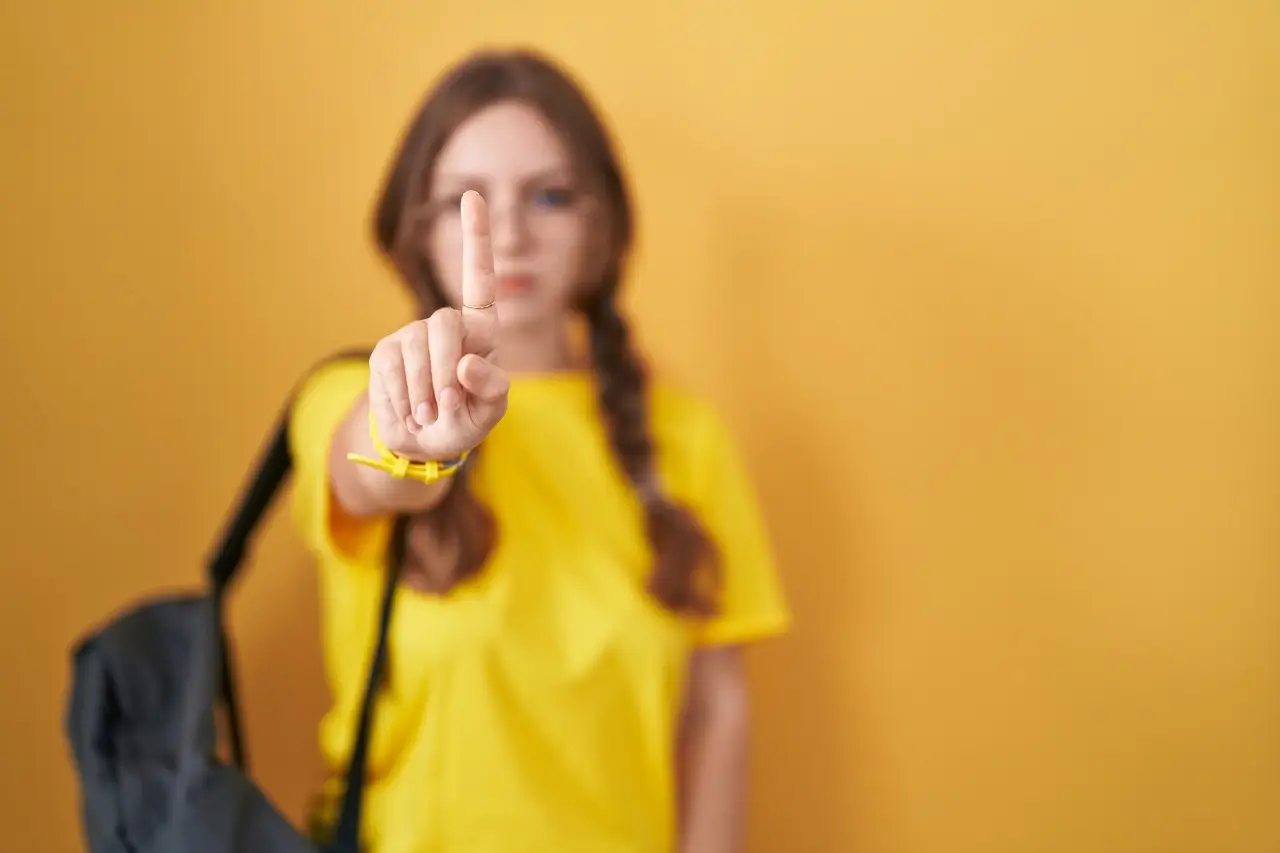 una mujer señala con el dedo sobre un fondo amarillo