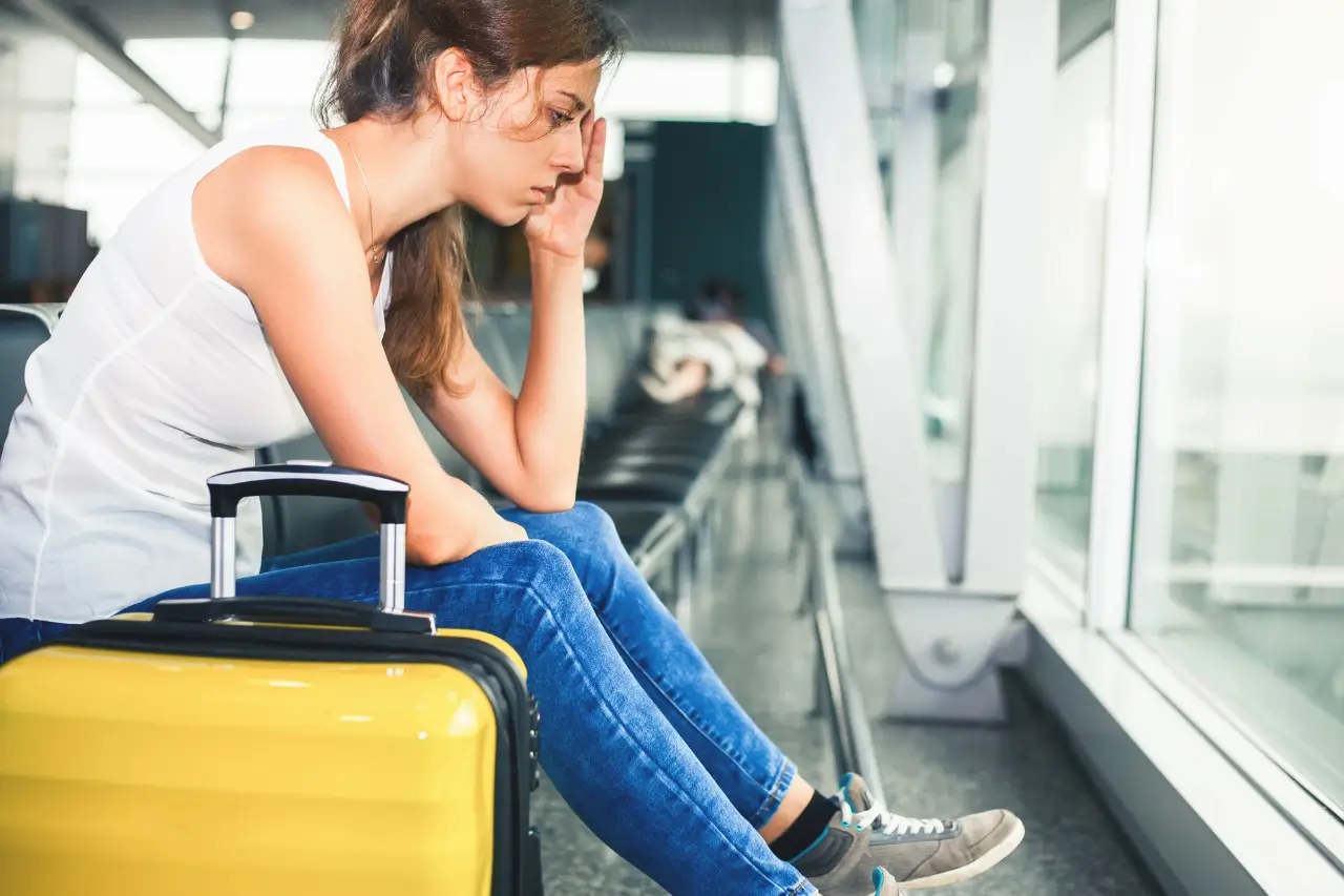 A woman sitting at the airport with her baggage