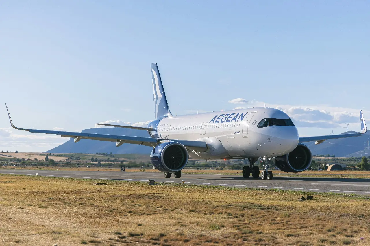 An Aegean Airlines plane on the runway with mountains in the distance.