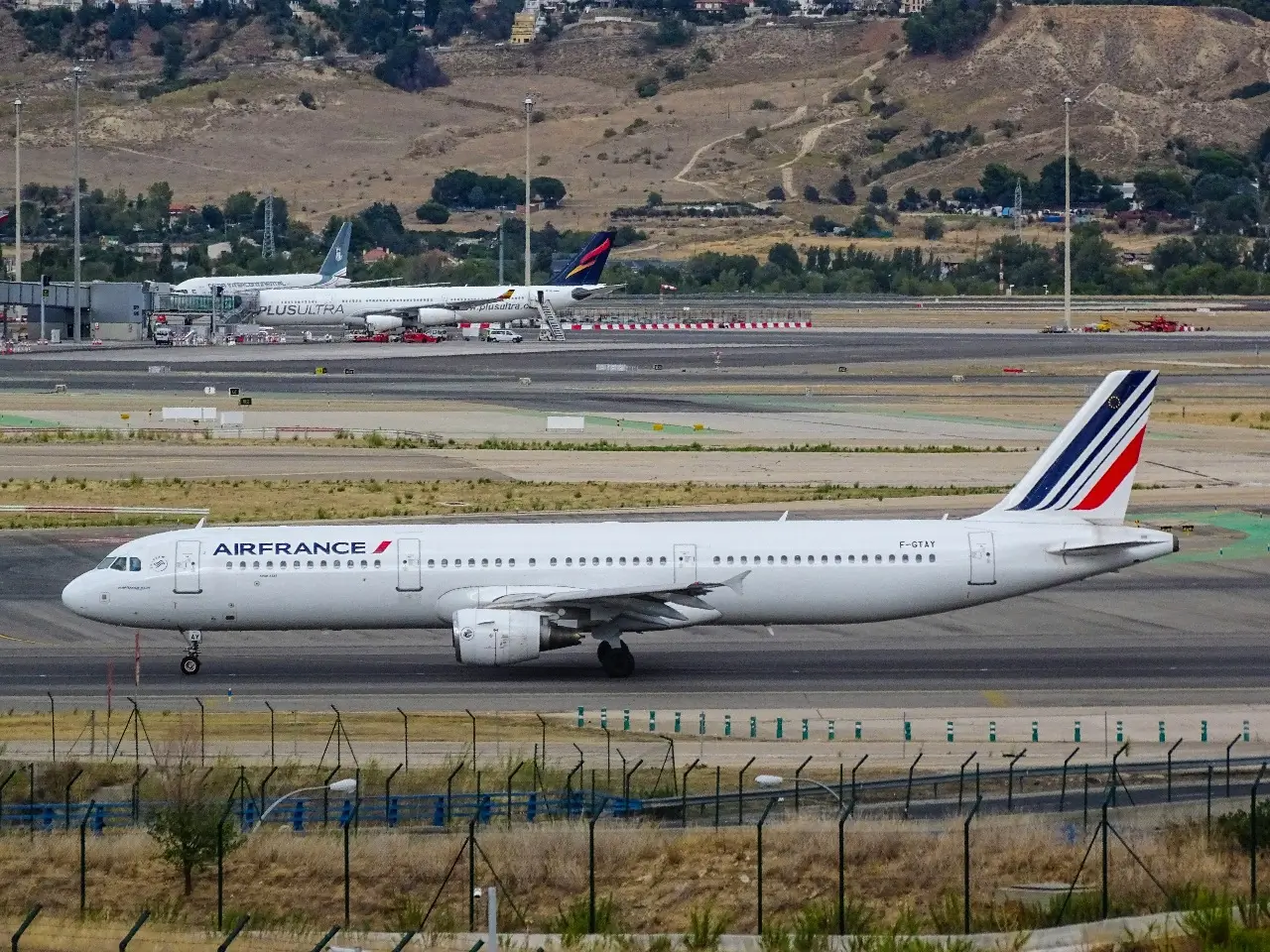 A white Air France plane on the tarmac surrounded by a dry landscape.
