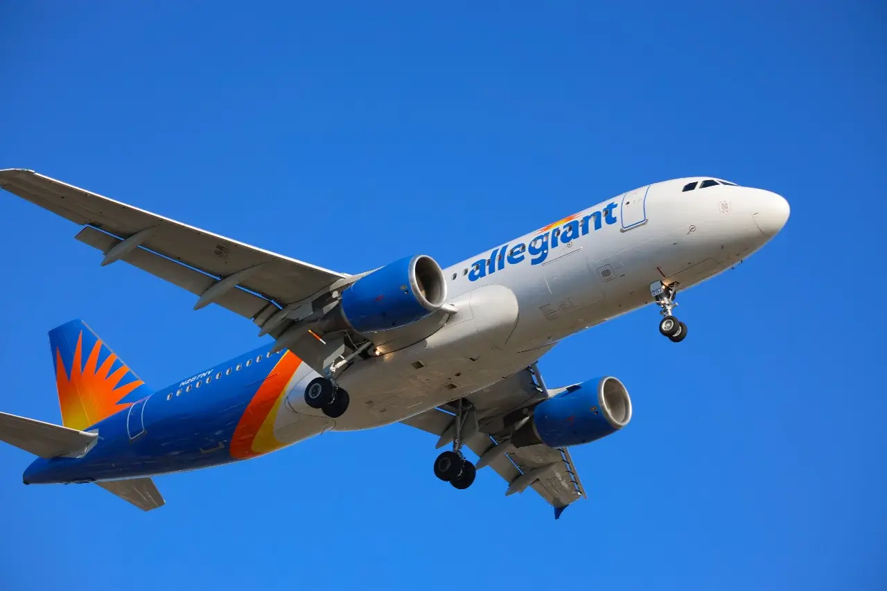An Allegiant Air plane after a delayed takeoff in a bright blue sky