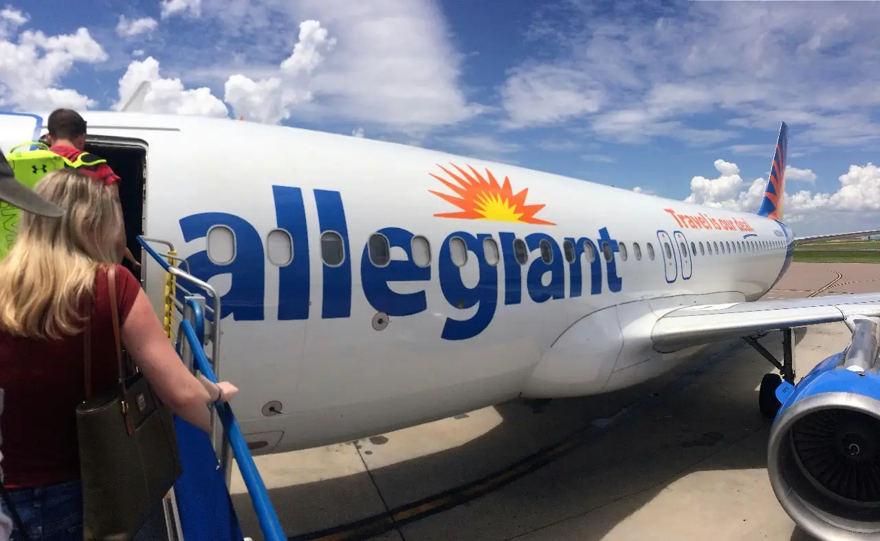 Passenger boarding a delayed Allegiant Air flight on a sunny day
