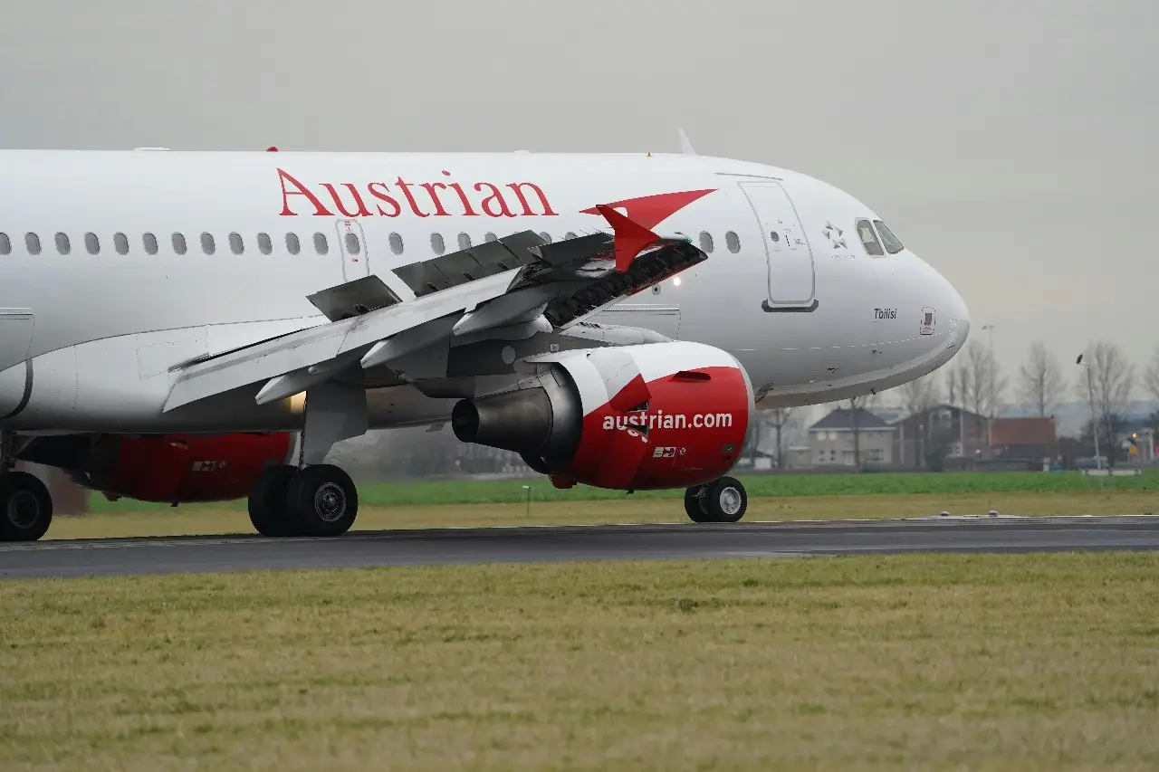 A close-up of a white and red Austrian Airlines plane on the runway in the fog
