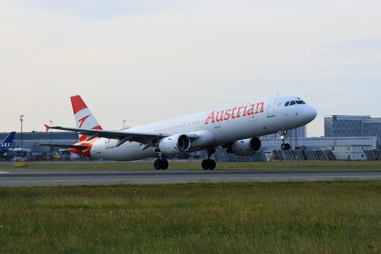 A white and red Austrian Airlines taking off at Copenhagen Airport.