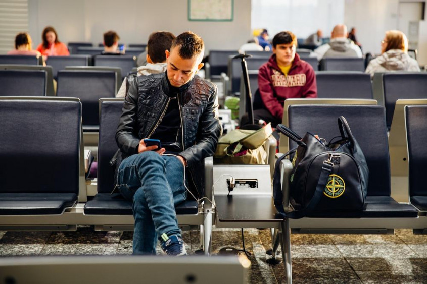 Bărbat în aeroport care caută cum să obțină o despăgubire pentru un zbor întârziat AirDolomiti