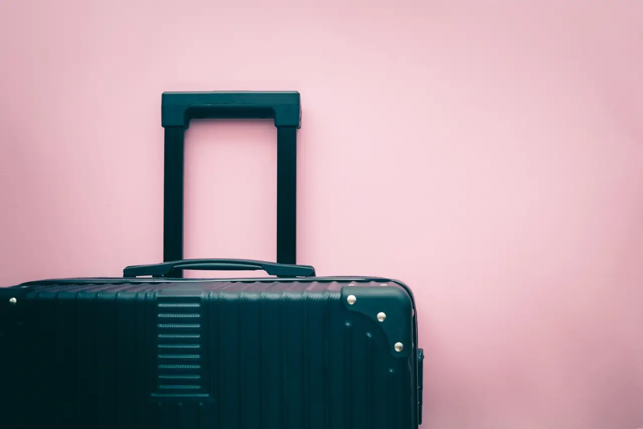 en svart resväska på en rosa bakgrund