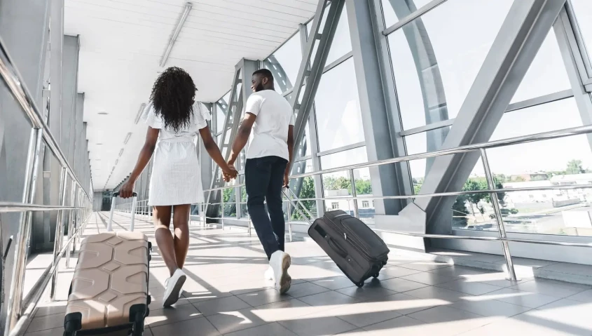 casal a caminhar num aeroporto com malas de viagem