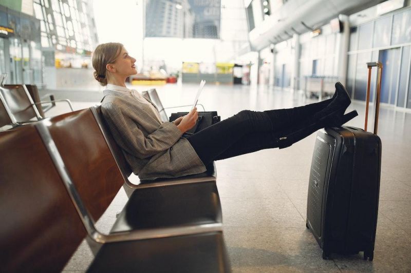 Frau sitzt wartend am Flughafen
