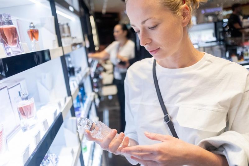 a woman purchasing perfume from the duty-free store at the airport
