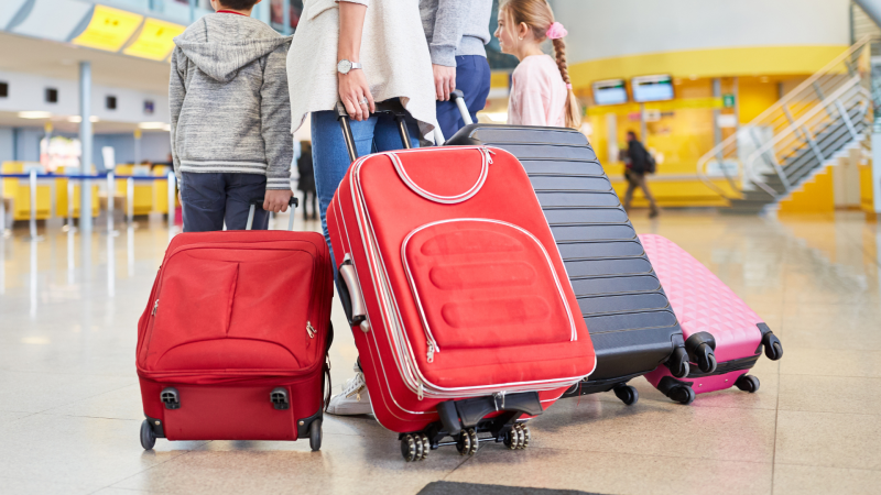 Familie mit roten Koffern am Flughafen