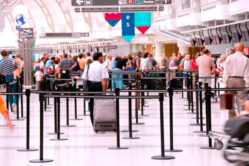 Fila de facturación de un aeropuerto llena de pasajeros esperando y comprobando cuál es la posibilidad de overbooking de vuelos