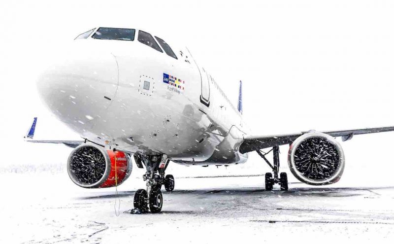 an airplane on the tarmac during a snowstorm