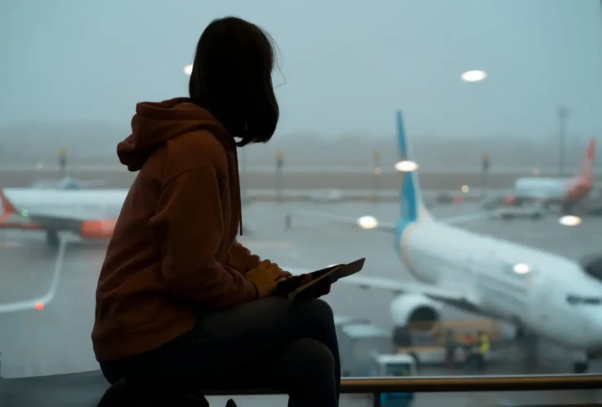 une femme attend son vol a cote d'une fen&ecirc;tre