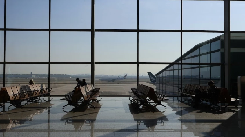 Sala de espera del aeropuerto de Bilbao con personas sentadas en las butacas.