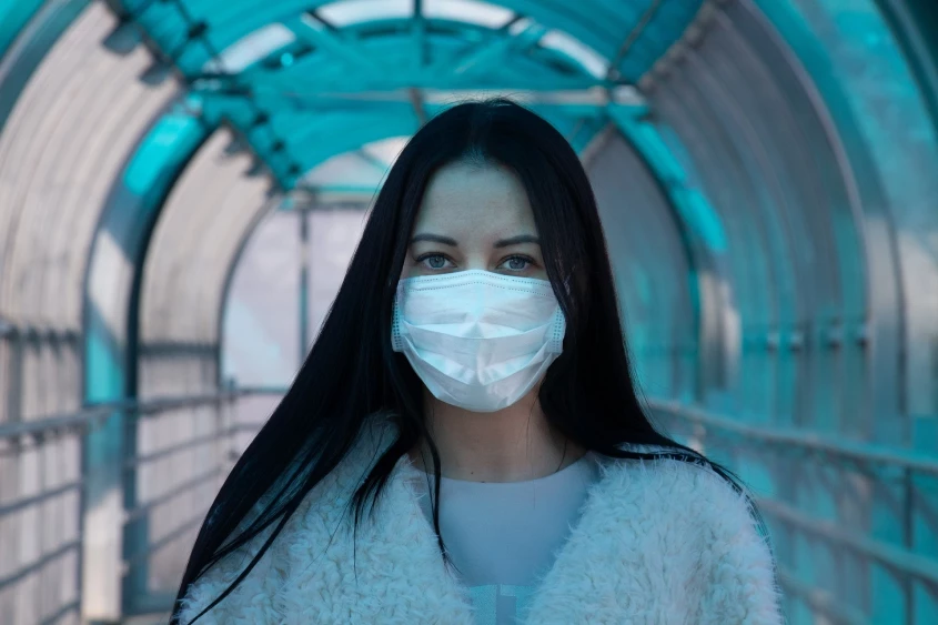 Genrebild över en kvinna på väg att gå av ett flygplan med mask över munnen
