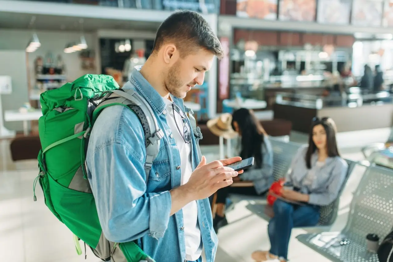 un homme avec un sac &agrave; dos vert dans un a&eacute;roport