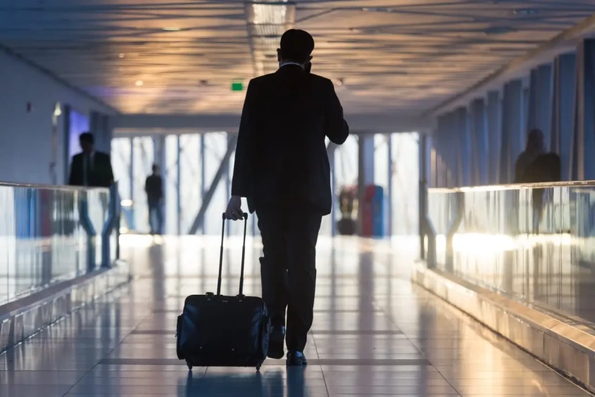un voyageur avec sa valise marche dans un a&eacute;roport
