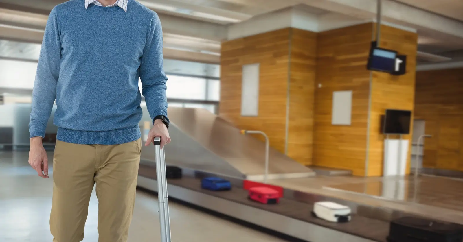 Mann mit Gep&auml;ck im Flughafen an der Gep&auml;ckausgabe