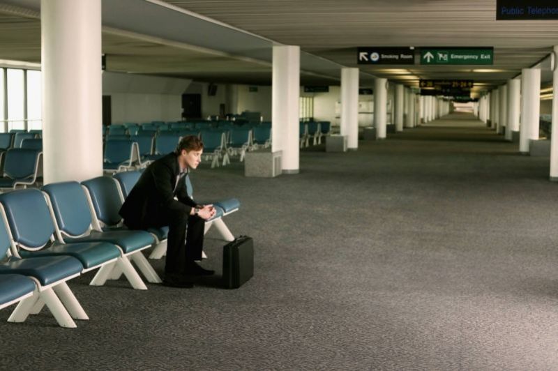 Mann sitzt wartend am Flughafen