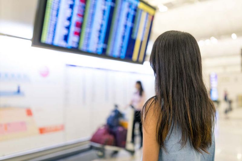 Pasajera mira en panel la cancelación de vuelos de Avianca