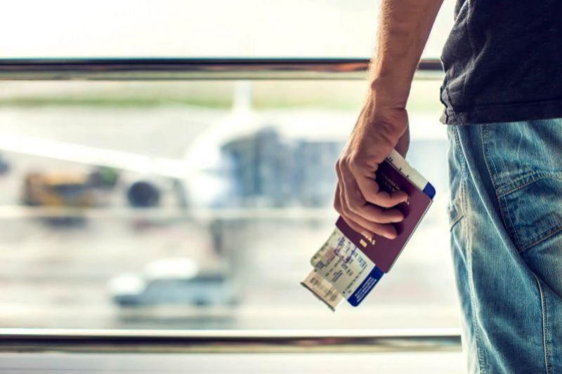 passagerare betraktar ett flygplan med sitt boardingkort och pass i handen