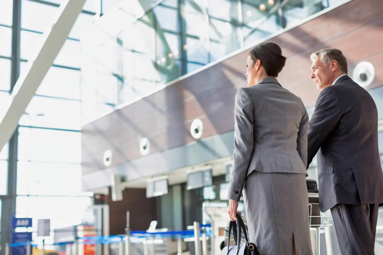 personnes enregistrant leurs bagages &agrave; l'a&eacute;roport