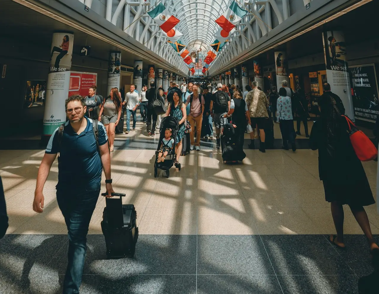 People walking down the busy concourse at Chicago&rsquo;s O&rsquo;Hare Airport with flags displayed prominently.
