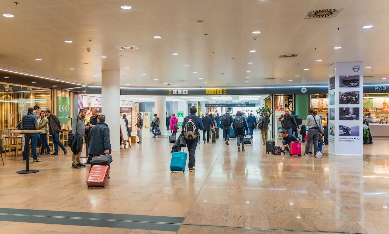 Reizigers met koffers lopen door de terminal van Brussels Airport na een vertraagde vlucht