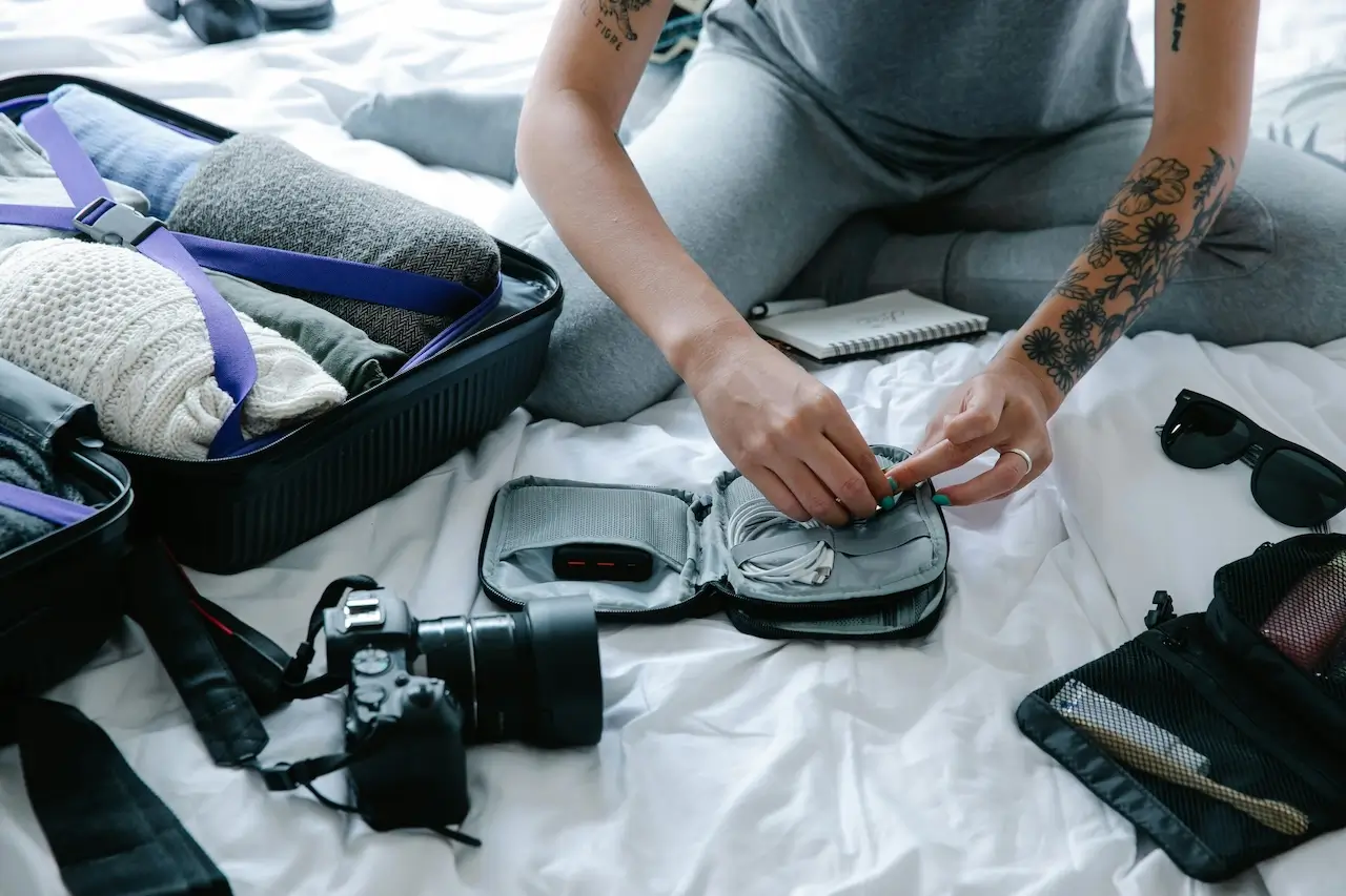 A person sitting on a bed packing their hand luggage